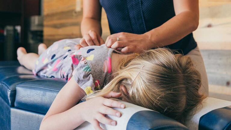 An older adult receiving a gentle chiropractic adjustment from a licensed practitioner in a clinic setting.